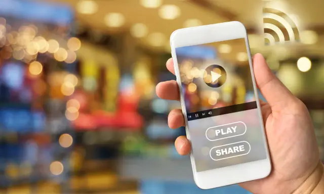 Dłoń trzyma smartfon Huawei, na ekranie którego widać interfejs odtwarzacza wideo z przyciskiem "PLAY" i "SHARE", sugerujący dostęp do treści z Google Play.