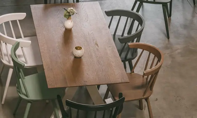 Holztisch mit bunten Stühlen und Deko-Elementen, aus der Vogelperspektive.