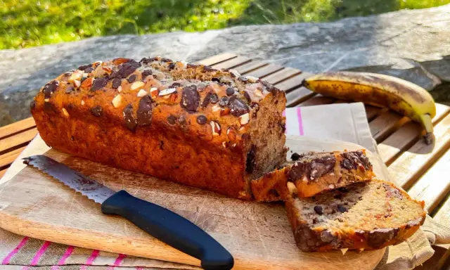 Delizioso banana bread vegano con gocce di cioccolato e mandorle, pronto per essere gustato all'aperto.