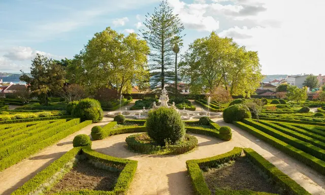 Ein barocker Garten mit Brunnen und akkurat geschnittenen Hecken vor dem Ajuda-Palast in Lissabon.