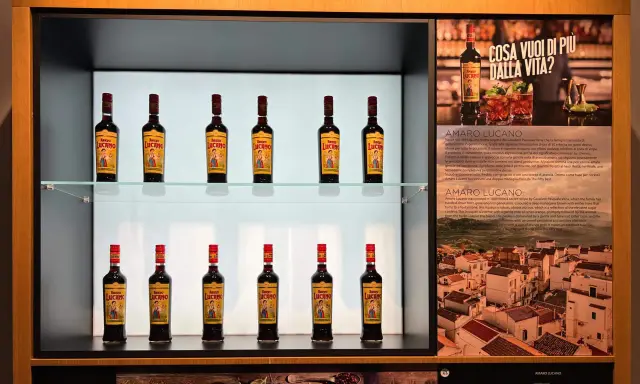 Butelki amaro Lucano stoją na półkach, tworząc elegancką ekspozycję.