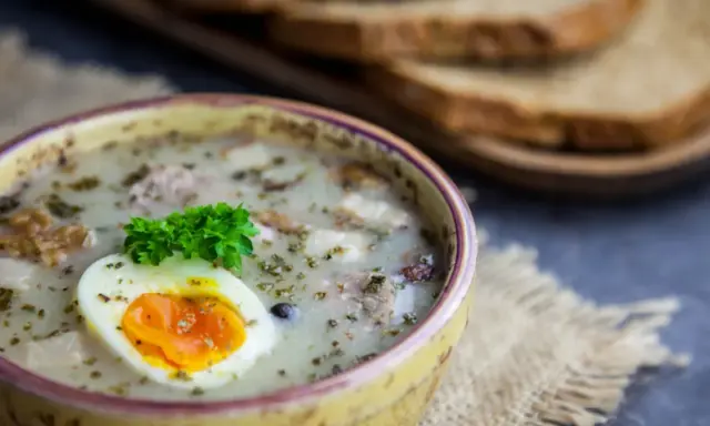 Żur z jajkiem i majerankiem, idealne jakie przyprawy do żuru. Obok kromki chleba.