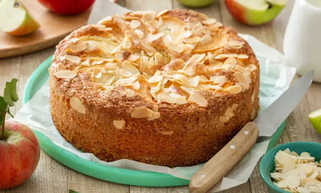 Un délicieux clafoutis aux pommes, parsemé d'amandes effilées, prêt à être dégusté. Une recette inspirée du carnet de Julie.