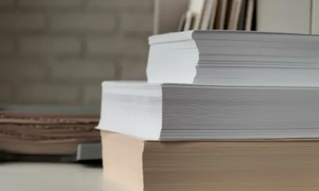 Stosy białego i beżowego papieru, gotowe do druku. Ten papier powlekany czeka na kreatywne projekty.