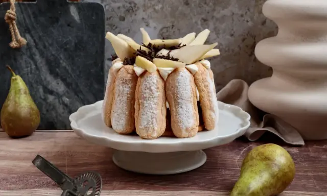 Charlotte poire chocolat, un dessert élégant avec des biscuits à la cuillère, garni de poires fraîches et de copeaux de chocolat.