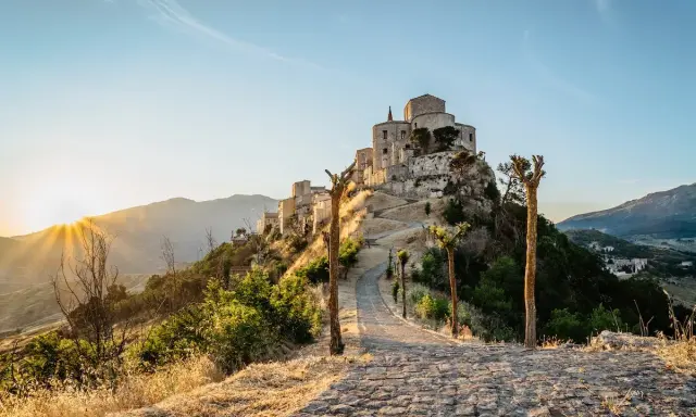 Petralia Soprana: cosa vedere in questo borgo arroccato, con un sentiero in pietra che sale verso il castello al tramonto.