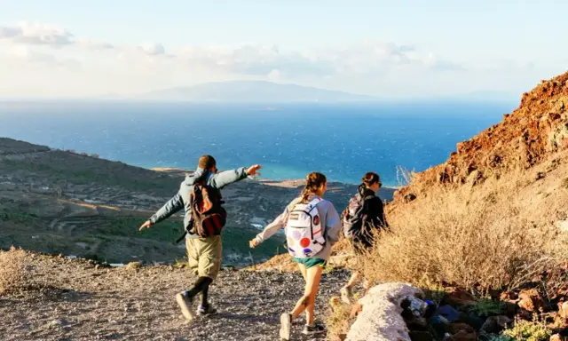 Vandrare njuter av utsikten över havet och landskapet på Santorini. En man pekar ut mot horisonten.