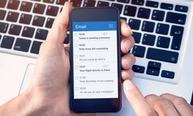 Dłoń trzyma smartfon z listą e-maili, w tym "Your flight tickets to Paris". Kiedyś, yours sincerely, wysłałbym takie wiadomości.