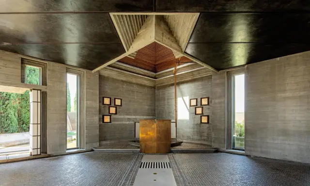 Interno moderno con altare dorato, pareti in cemento grezzo e soffitto a punta. Un esempio di architetti famosi italiani.