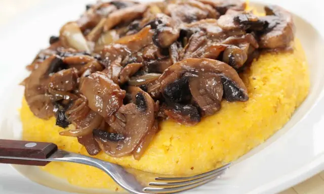 Polenta con funghi trifolati, un classico tra i cibi tipici del Trentino Alto Adige, pronta per essere gustata.