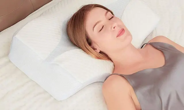Mujer durmiendo plácidamente sobre una almohada ergonómica. Aprende como colocar la almohada correctamente para un descanso óptimo.