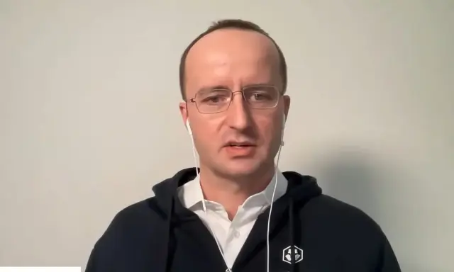 Kris Marszalek, CEO Crypto.com, w okularach i słuchawkach, w czarnej bluzie z logo.
