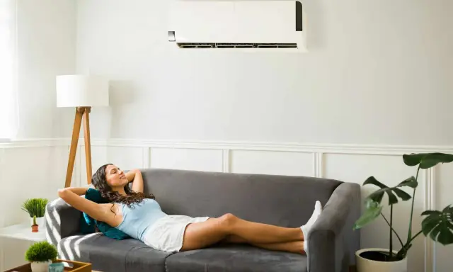Une femme se détend sur un canapé sous un climatiseur, profitant de la puissance clim pour 40m2.