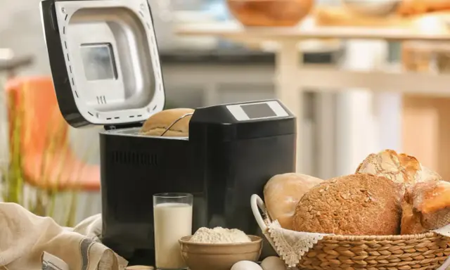 Machine à pain ouverte, avec du pain frais dans un panier. Avis sur la machine à pain : facile et pratique pour un pain maison.