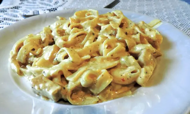 Pyszne tagliatelle z kurczakiem w kremowym sosie, podane na białym talerzu.