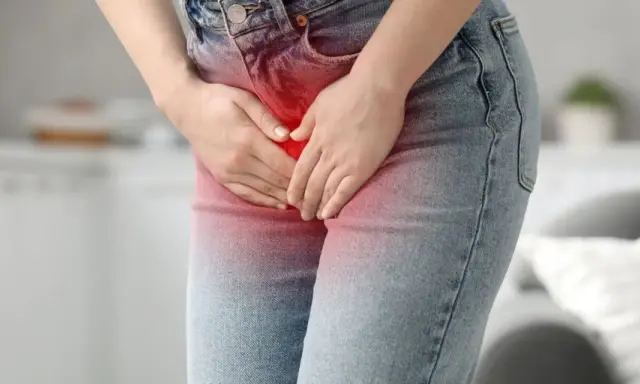 Kobieta trzyma się za podbrzusze, odczuwając ból brzucha przy zapaleniu pęcherza.
