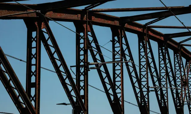 Estructura de puentes de hierro famosos contra el cielo azul. Cables cruzan la intrincada red de vigas oxidadas.