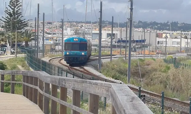 Ein Zug fährt auf den Gleisen in Richtung einer Marina mit vielen Segelbooten. Die Fahrt von Lissabon in die Algarve ist ein Erlebnis.