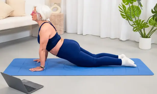 Donne di 50 anni in forma, praticano yoga a casa seguendo un tutorial online.