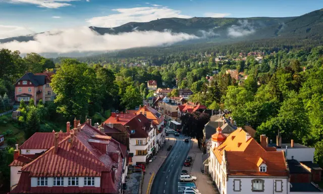 Widok na malowniczy rynek w Szklarskiej Porębie z czerwonymi dachami i otaczającymi go zielonymi wzgórzami Karkonoszy.