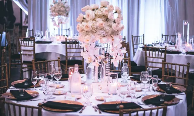 Elegancka sala weselna z kwiatową dekoracją i nakrytymi stołami. Idealne miejsce, by zacząć planowanie, jak napisać maila o salę weselną.