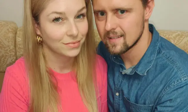 Zbliżenie na twarze pary siedzącej obok siebie na kanapie.
