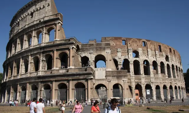 Le Colisée de Rome avant sa restauration complète, avec des touristes admirant son architecture antique sous un ciel bleu.
