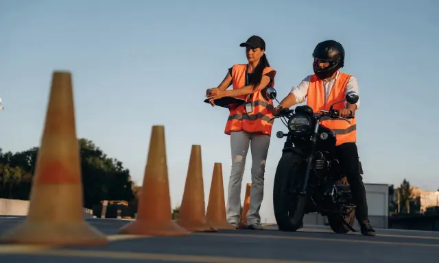 Instruktorka motocyklowa obserwuje kursanta podczas ćwiczeń na placu. Zastanawiasz się, ile godzin jazdy na kat. A potrzeba, by zdać egzamin?