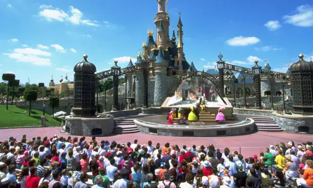 Disneyland Paris con niños: un espectáculo de princesas frente al castillo, con una multitud emocionada disfrutando del día.