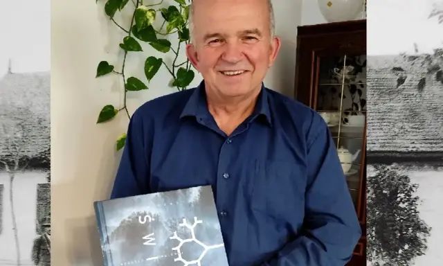 Uśmiechnięty mężczyzna trzyma książkę "Świat". Czyżby to był gajowy, który opowiada o leśnych tajemnicach?
