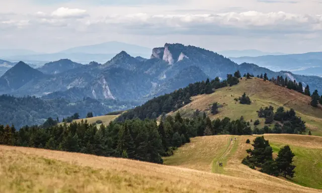 Malowniczy krajobraz górski, idealny na szczawnica trasę. W oddali skaliste szczyty, bliżej zielone wzgórza i ścieżka dla turystów.