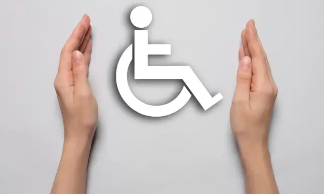 Dwie dłonie otaczają biały symbol osoby na wózku inwalidzkim, symbolizując wsparcie i akceptację dla osób z niepełnosprawnościami.
