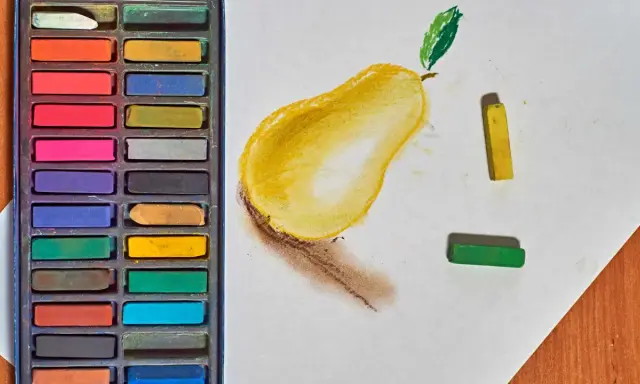 Boîte de pastels secs et une poire dessinée. Apprenez comment faire des pastel en utilisant ces couleurs vives.