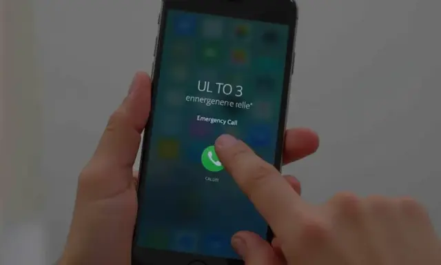 Dłoń naciska przycisk "Emergency Call" na ekranie telefonu, pokazując, jak odblokować telefon przez połączenie alarmowe.