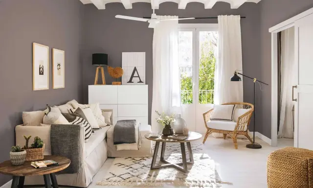 Salones pequeños con encanto: un sofá beige, sillón de mimbre, mesas de madera y detalles decorativos crean un espacio acogedor.