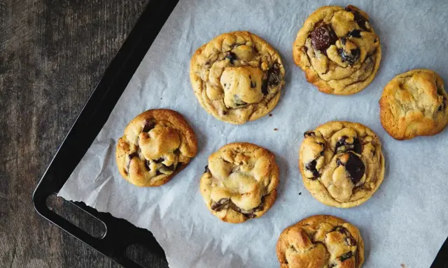 Sept cookies américains aux pépites de chocolat, tout juste sortis du four, prêts à être dégustés. Une recette de cookie américain parfaite !