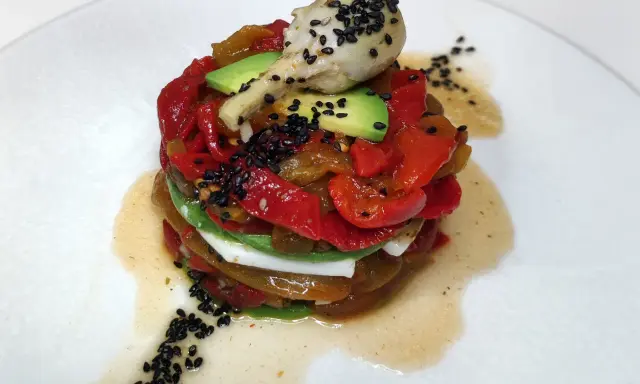 Torre de pimientos del piquillo asados, aguacate y queso fresco, coronada con un alcachofa y semillas de sésamo negro.