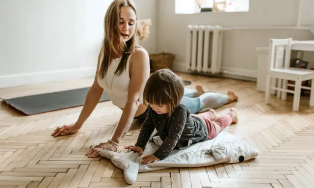 Mama i dziecko ćwiczą jogę. To świetne gry i zabawy ruchowe przykłady dla całej rodziny.