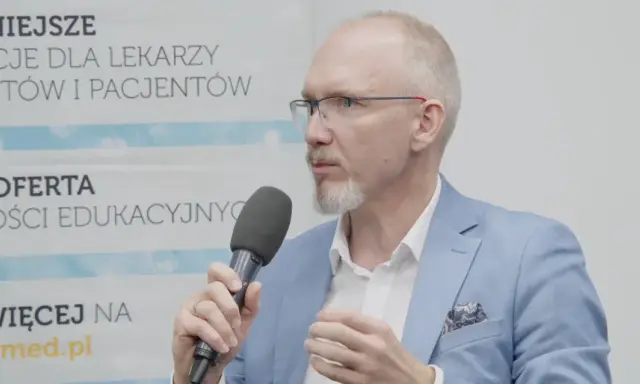 Mężczyzna w okularach i niebieskiej marynarce mówi do mikrofonu, omawiając nowe podejście do leczenia astmy, jakby to był jego własny asthma rap.