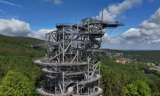 Metalowa konstrukcja z drewnianymi platformami tworzy niezwykły sky walk pośród zielonych lasów. Widok zapiera dech w piersiach.