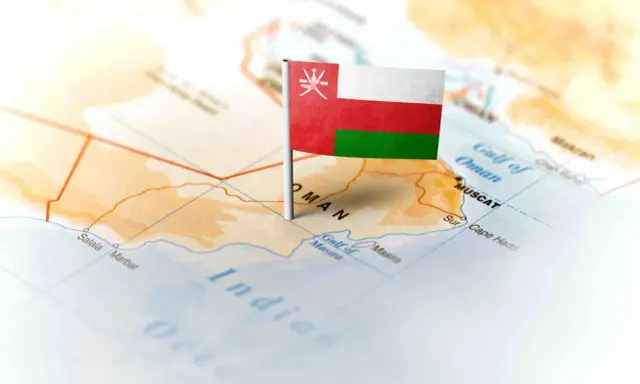 Flaga Omanu wbita w mapę, wskazująca gdzie leży Oman, nad Zatoką Omańską, w pobliżu Maskatu.