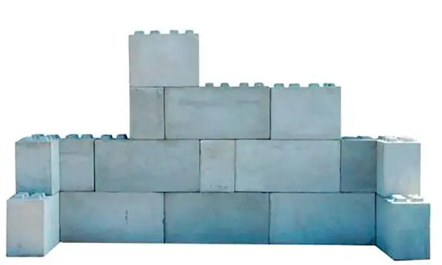 Una pared de bloques grises, apilados de forma irregular, simula un castillo de juguete.