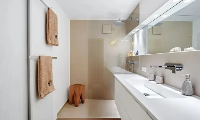 Bagno moderno con lavabo bianco, doccia a pioggia e dettagli in legno. Ottime idee per arredare bagno con stile minimalista.