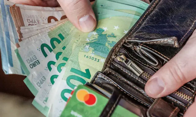 Dłonie trzymające portfel z banknotami euro. Od 2015 roku jaka waluta jest na Litwie? Euro.