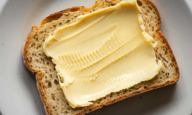Eine Scheibe Brot mit einer dicken Schicht Butteralternative, die gut für die Cholesterinwerte ist.