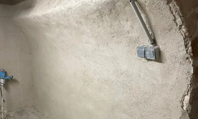 Murs bruts avec prises électriques et tuyauterie, étape clé pour savoir comment assainir une maison.