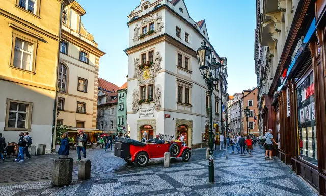 Uliczka w Pradze z czerwonym kabrioletem i zabytkowymi kamienicami. Złota uliczka Praga zachwyca.
