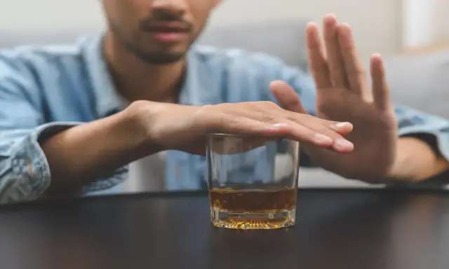 Mężczyzna odrzuca szklankę z alkoholem, symbolizując walkę z nałogiem. To obraz przymusowego leczenia alkoholika, który decyduje się na zmianę.