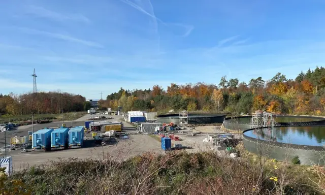 Baustelle mit großen Wasserbehältern und blauen Containern. Hier wird gezeigt, wie funktioniert geothermie mit Erdwärme.