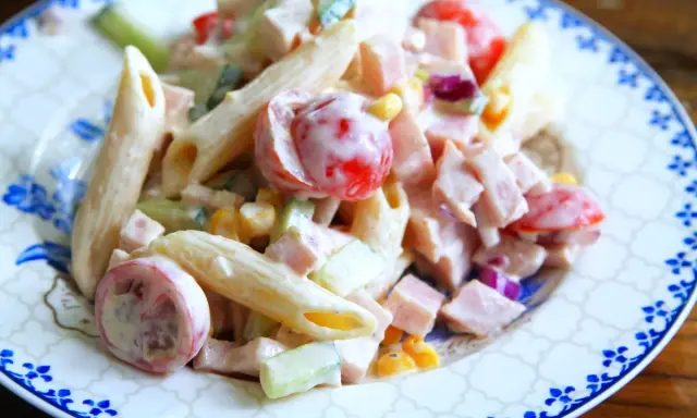 En krämig pastasallad med kassler, penne, körsbärstomater, gurka och majs. Perfekt för en snabb och god lunch.